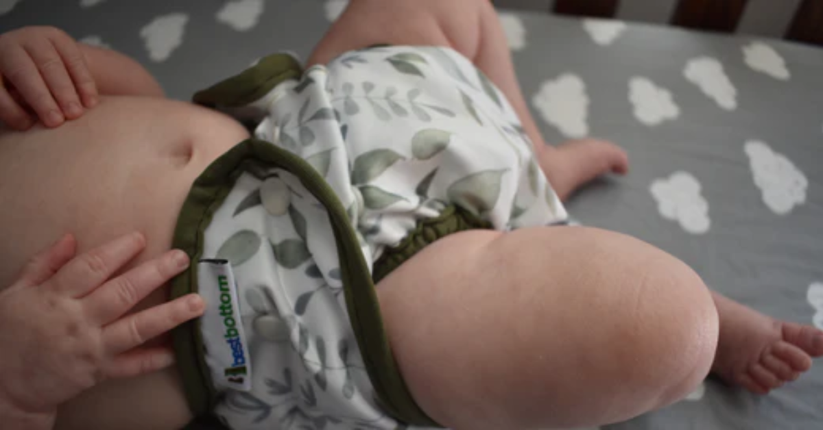 baby wearing a cloth diaper on a changing table